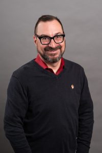 man with glasses and beard wearing  a sweater,